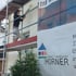 Maler streicht eine Hauswand von einem Gerüst aus, daneben ein Banner von "Sven Horner Maler + Lackierer".