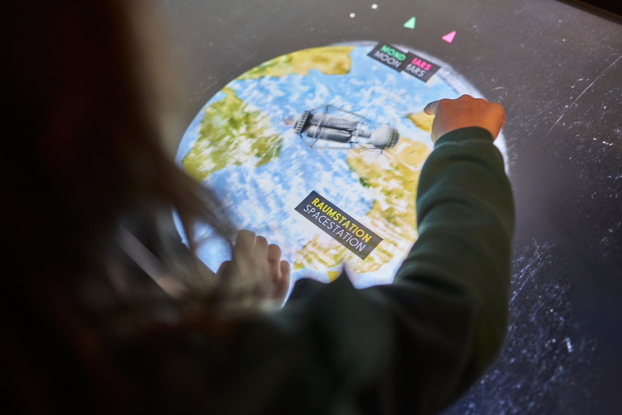 Am interaktiven Exponattisch steuern Besucherinnen und Besucher ihre Reise zu Mond, Mars und Raumstation