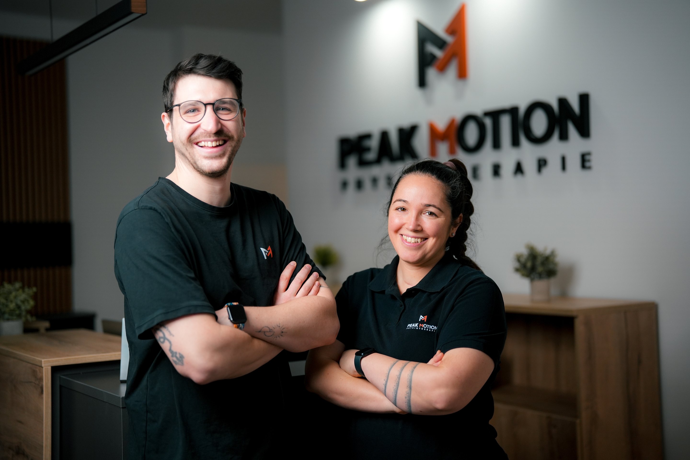 Quinn und Jennifer Kriewall vor dem Peak-Motion-Logo am Empfang der Praxis in Hamburg-Langenhorn