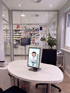 Ein Tablet auf einem ovalen Tisch zeigt einen stilisierten Arzt in einer Apotheke mit Medikamentenregalen.
