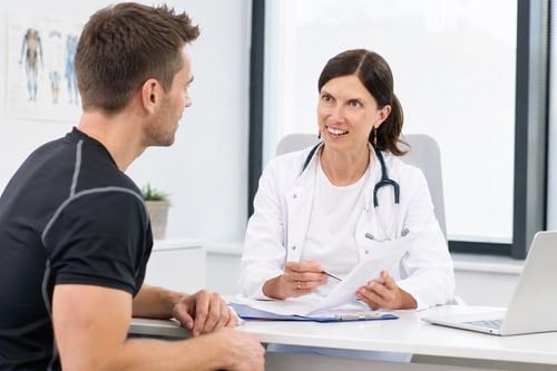 Ärztin und Patient besprechen die Befunde am Schreibtisch