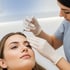 Woman getting a forehead cosmetic injection from a gloved professional