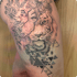 Tattoo auf einem Oberschenkel mit Tigerkopf, Frauengesicht, Blumen, Schmetterling und geometrischen Dreiecken.