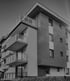 Modernes Mehrfamilienhaus in Schwarz-Weiß mit Balkonen und Holzfassade.