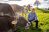 Christian Manser kniet auf einer grünen Wiese neben vier Kühen
