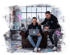 Zwei lachende Männer in einem modernen Büro mit Laptop, Design-Layouts und leuchtenden Cursor-Symbolen.