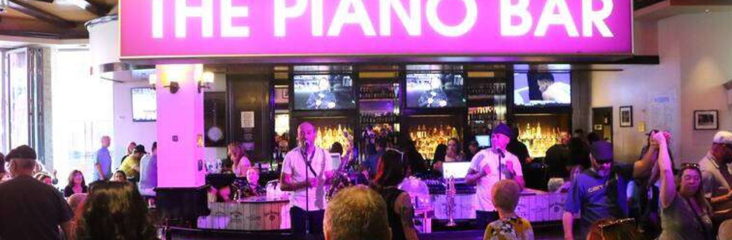 The Piano Bar at Harrah's Las Vegas, pianos and a crowd under the pink neon sign