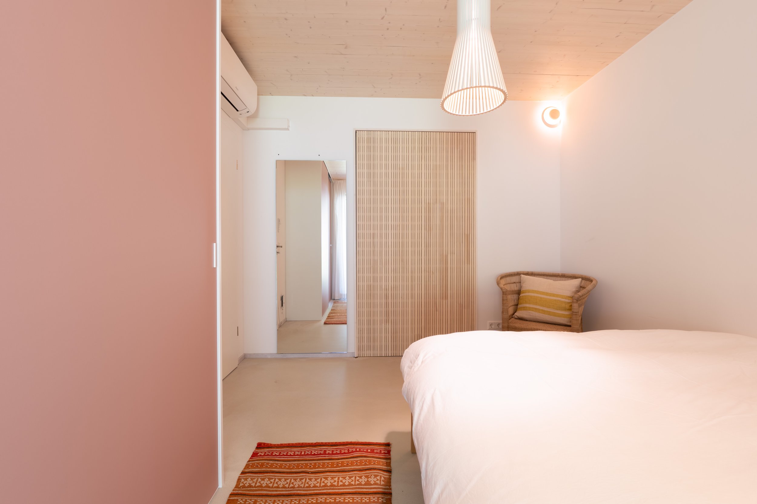 Schlafzimmer mit altrosa Wand und Blick ins Bad
