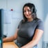 Lächelnde Frau mit Headset im Büro am Schreibtisch.