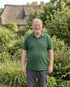 Volker Möller von Volker Möller GalaBau in Wedel im grünen Firmenpolo vor einem Reetdachhaus.