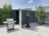 Gartenschuppen aus Metall mit offener Tür, Grill und Skulptur auf einer Terrasse.