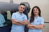Mann und Frau in hellblauen Poloshirts mit gekreuzten Armen vor einem dunklen Lieferwagen.