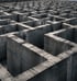 Betonlabyrinth mit hohen, grauen Wänden unter leicht bewölktem Himmel.