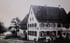 Schwarz-Weiß-Foto eines Gasthauses mit Schild "Gasthaus zum Lamm" und einer Gruppe von acht Kindern davor.