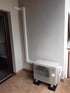 Eine weiße Fujitsu-Klimaanlage steht auf einem gefliesten Balkon neben einer Wand mit einer weißen Abdeckung.