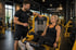 Ein Personal Trainer hilft einer Frau beim Beintraining an einer Maschine im Temple Gym Dresden.