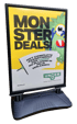 A black A-frame sign displays "MONSTER DEALS!" with a green monster, and text in Dutch promoting Unger cleaning tools.