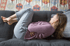 Woman curled on sofa holding stomach, highlighting pelvic floor health.