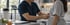 A healthcare professional in blue scrubs uses a white measuring tape to check a patient's waist circumference in a clinic.