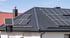 Dunkles Ziegeldach eines Hauses mit mehreren Photovoltaikmodulen und einem externen Solarpanel.