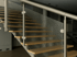 Holztreppe mit Glasgeländer und Metallhandlauf.