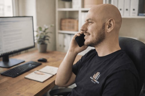 Mann telefoniert lächelnd am Schreibtisch