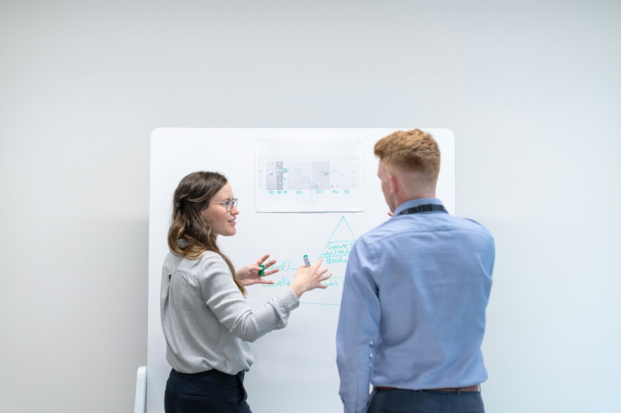 Zwei Kollegen besprechen an einem Whiteboard eine Skizze