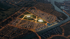 Aerial night view of a sprawling city with illuminated buildings, roads, and two large circular structures.
