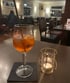 Ein Glas Aperol Spritz mit Strohhalm und eine Teelichtkerze auf einem Tisch in einem Restaurant.