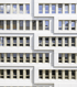 Moderne weiße Gebäudefassade mit einem geometrischen Zickzack-Muster und gleichmäßig angeordneten Fensterreihen.