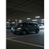 Graues SUV in einem Parkhaus mit Deckenleuchten und anderen Autos im Hintergrund.