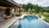 Luxuriöser Poolbereich mit Liegestühlen, angrenzender Terrasse, Sitzgelegenheiten und üppiger Gartenlandschaft.