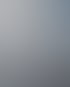 Arzt mit Brille, hellblauem Hemd und Stethoskop sitzt mit verschränkten Armen in einer Praxis.