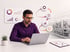 Man in purple shirt and glasses working on laptop, with data dashboards and a process flow diagram.