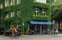 Grün bewachsenes Gebäude mit blauem Vordach über dem "RÖMERPARK CAFEHAUS RÖMERPARK" steht. Menschen sitzen davor.