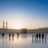 Pilger gehen bei Sonnenuntergang über den Platz der Großen Moschee in Mekka mit Blick auf die Kaaba.