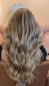 Rückansicht einer Person mit langen, gewellten Haaren in Balayage-Optik mit blonden und braunen Strähnen.