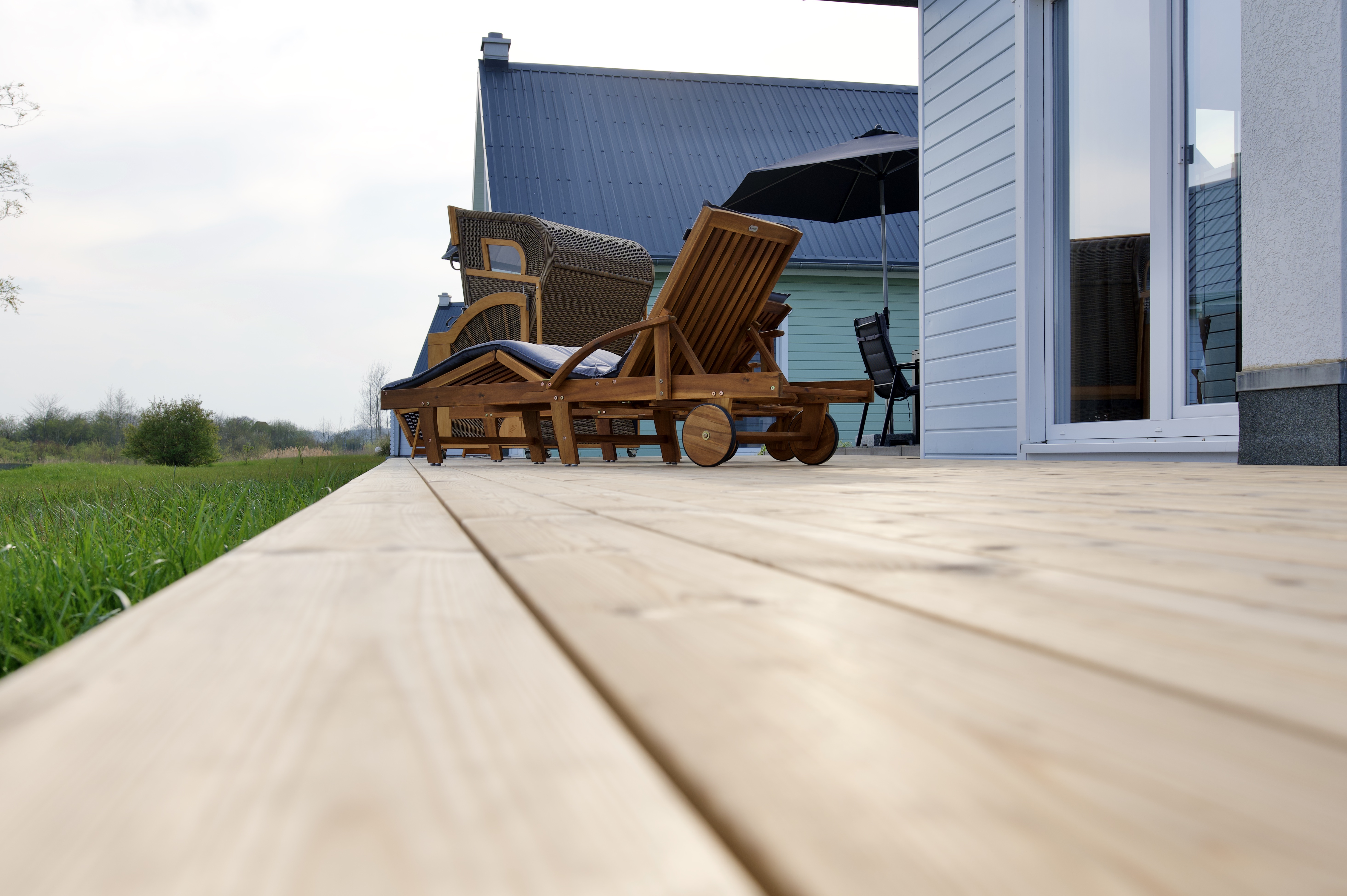 Skipper Galerie im OstseeResort Olpenitz – Detailansicht einer Holzterrasse mit Liegestühlen am Ferienhaus