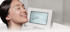 Lächelnde Frau mit strahlender Haut neben einem Hydrafacial-Gerät mit der Display-Aufschrift „Get your glow!“.
