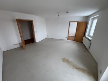 Leeres Zimmer mit rohem Estrichboden und zwei Türen