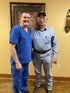 A doctor in scrubs smiling with an older man.