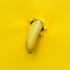 Eine gelbe Banane ragt aus einem Loch in gelbem Papier.