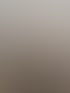 Rückenansicht einer Person mit glattem, langem, blondem Haar und schwarzen Oberteil vor einer Wand mit Wellenmuster.