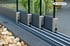 Graues Aluminium-Bodensystem mit Glasgeländer und Steinen davor.