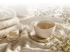 Tasse mit Kräutertee neben einem Stapel Handtücher und einem Tiegel Hautcreme in warmem Sonnenlicht.