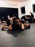Mehrere Männer trainieren Brazilian Jiu-Jitsu auf einer Matte in dem Kampfiq Studio.