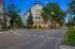 Straßenecke mit beleuchtetem weißen Gebäude, Bäumen und leerer Straße bei Dämmerung.