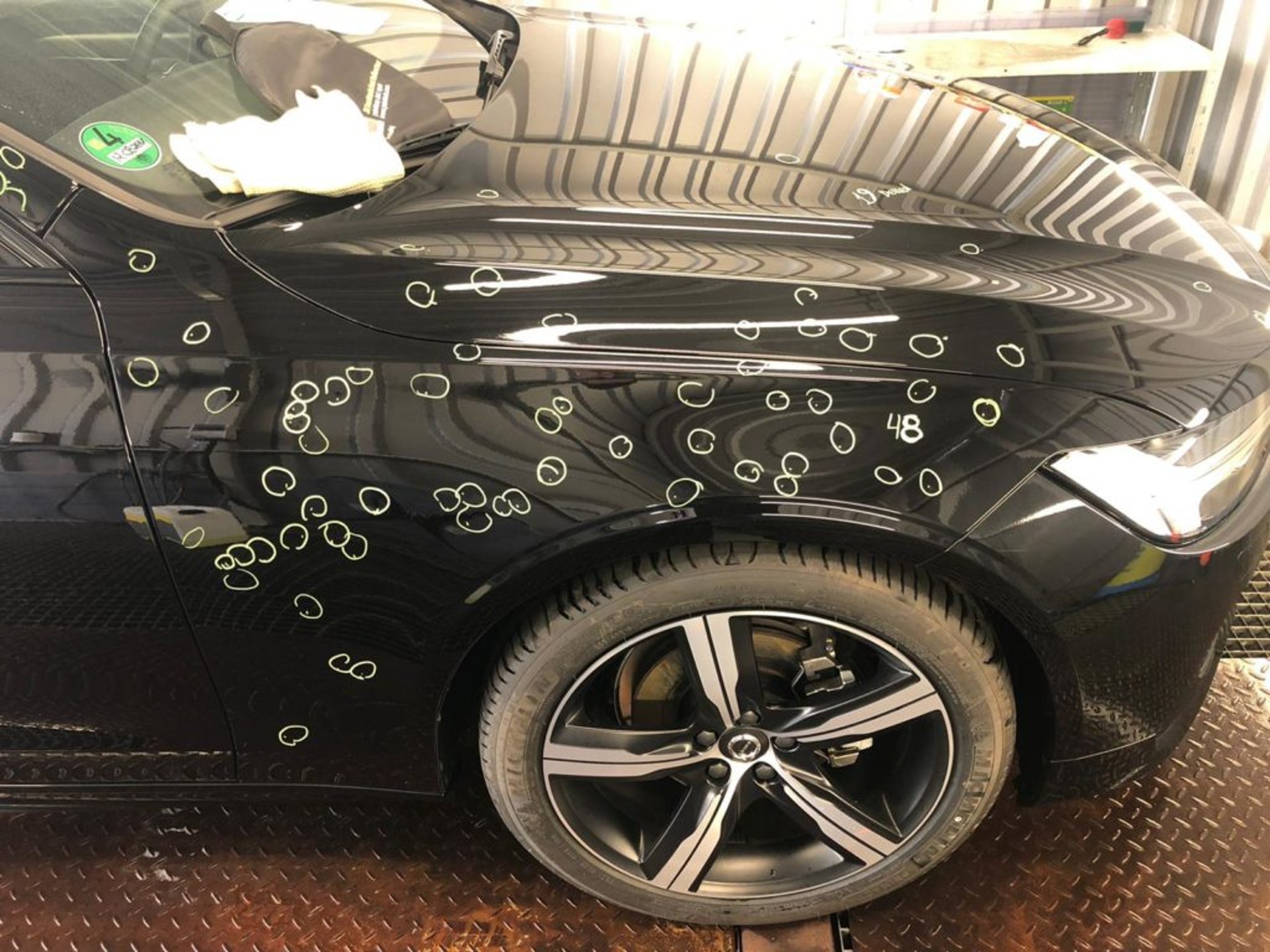 Schadensaufnahme an einem schwarzen Fahrzeug, jede einzelne Delle ist markiert