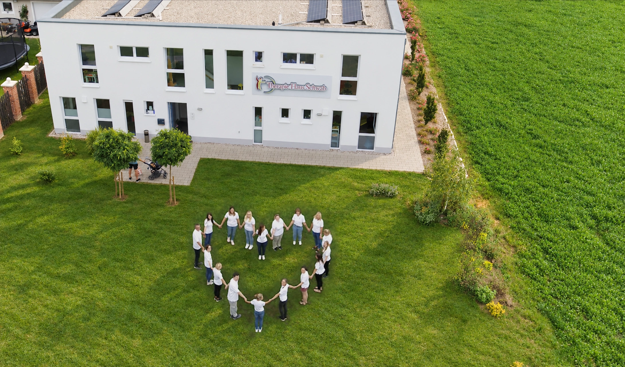 Luftaufnahme des Therapie Haus Schwab mit dem Team in Herzform auf der Wiese