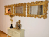Drei goldene Barockspiegel hängen über einer weißen Kommode mit goldener Vogelstatue und Ananas-Dekoration.